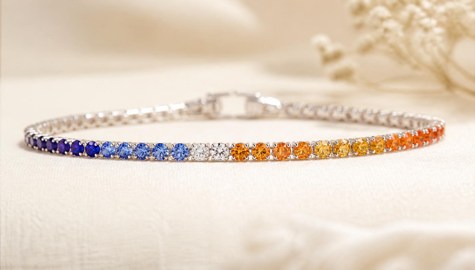 Fine tennis bracelet in blue sapphires flowing to orange and amber stones