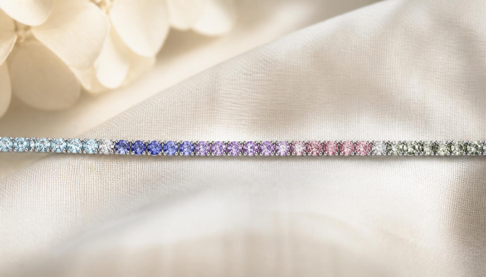 Fine tennis bracelet graduating through blue, violet, pink and green stones